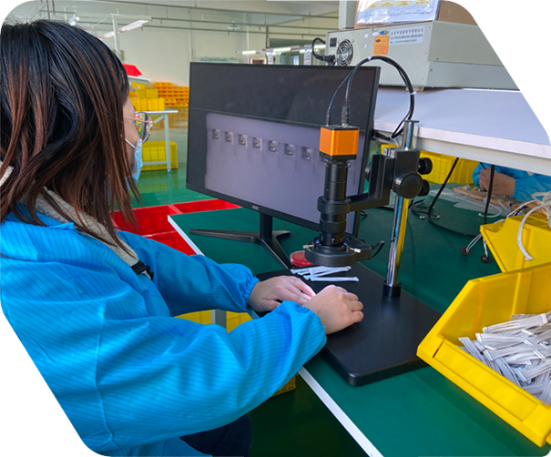Worker inspecting cable assembly components under a magnification tool
